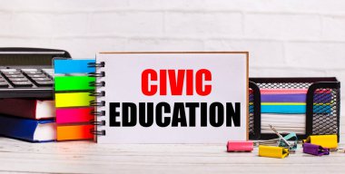 On a light wooden background, a calculator, multi-colored sticks and a notebook with the text CIVIC EDUCATION. Business concept clipart