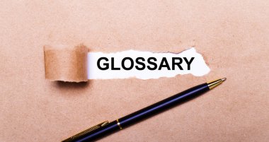 Yırtık Kraft kağıdı, GLOSSARY yazılı beyaz arkaplan. Yakınlarda siyah bir kol var. Yukarıdan görüntüle