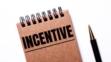 Hafif arkaplanda siyah bir kalem ve siyah yaylar üzerine kahverengi bir defter var.