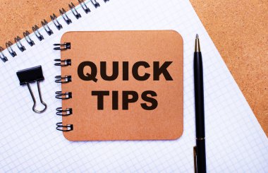 Tahta arka plan not defteri, siyah kalem, ataç ve QUICK TIPS yazılı kahverengi not defteri. İş konsepti