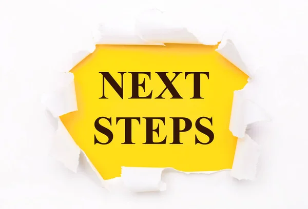 Yırtık beyaz kağıt parlak sarı bir zemin üzerinde yatar NEXT STEPS metni