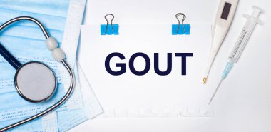 Arka planda bir stetoskop, bir elektronik termometre, bir şırınga, bir yüz maskesi ve Gout yazılı bir kağıt bulunur. Tıbbi konsept