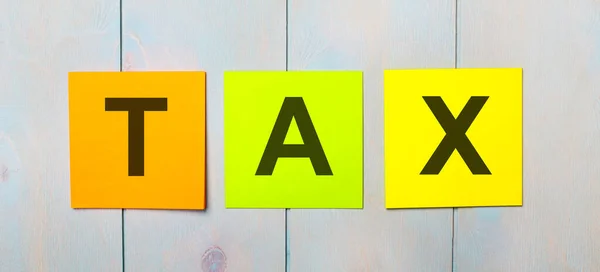 Drei Farbige Aufkleber Mit Dem Text Tax Auf Hellblauem Holzhintergrund — Stockfoto