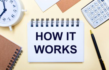 Hafif bir arkaplanda, beyaz bir çalar saat, bir hesap makinesi, bir kalem ve nasıl çalıştığı yazılı bir defter. Düz yatıyordu