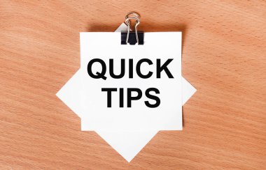 Siyah bir ataçın altındaki ahşap bir masanın üzerinde beyaz bir kağıt ve QUICK TIPS yazılı.