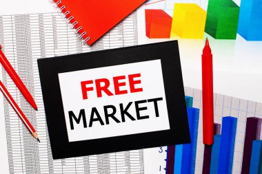 Raporlar ve renk çizelgeleri masada. Ayrıca siyah çerçevede kırmızı kalemler, kalemler ve kâğıtlar var ve içinde FREE MARKET yazıyor. Yukarıdan görüntüle