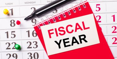 Takvimde FISCAL Yılı yazılı beyaz bir kart var. Yakınlarda kırmızı bir not defteri ve işaret var. Yukarıdan görüntüle