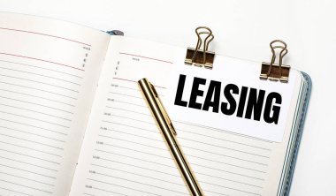 Hafif bir arka planda, açık bir defter, içinde altın ataçlar olan bir kağıt ve metin kaldırma ve bir altın kalem. Yukarıdan bak. İş konsepti