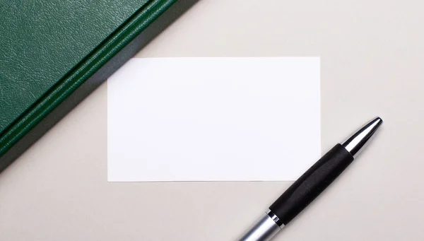 在浅灰的背景上 有一支钢笔 一个绿色笔记本和一张白色空白卡片 上面有一个插入文字的地方 商业概念 — 图库照片