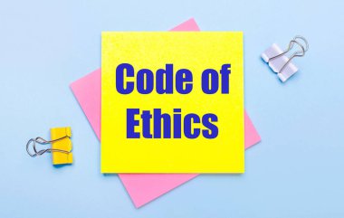 Açık mavi arka planda, sarı ve beyaz ataçlar, pembe ve sarı yapışkan notlar var.