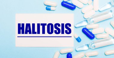 Haplar, ampuller ve açık mavi arka planda HALITOSIS yazılı beyaz kart. Tıbbi konsept