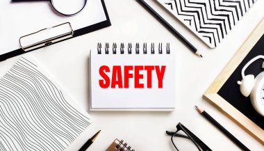 Bir ışık masasında defterler, bir büyüteç, bir çalar saat, bir gözlük ve bir kalem vardır. Ortasında da güvenli metin içeren bir defter var.