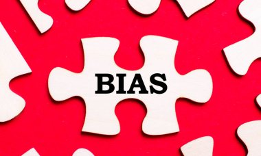 Parlak kırmızı arka planda, beyaz bulmacalar. Bulmacanın parçalarından birinde, BIAS metni