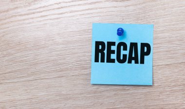 On a light wooden background - a light blue square sticker with the text RECAP