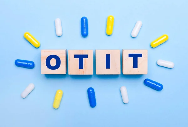 Light Blue Background Multicolored Pills Wooden Cubes Text Otit Medical — Stock Photo, Image
