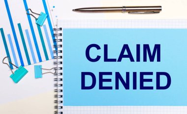 Açık arkaplanda - açık mavi diyagramlar, ataçlar ve CLAIM DENIED yazılı bir kağıt. Yukarıdan bak. İş konsepti