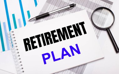 Masanın üzerinde raporlar, şemalar, bir kalem, bir büyüteç ve üzerinde RETIREREMENT PLAN metni olan beyaz bir not defteri var. İş konsepti