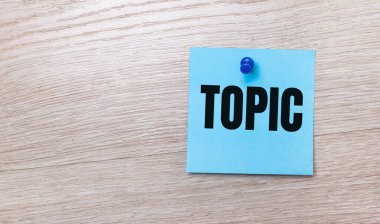 Açık ahşap bir arkaplanda - TOPIC yazılı açık mavi bir kare etiketi