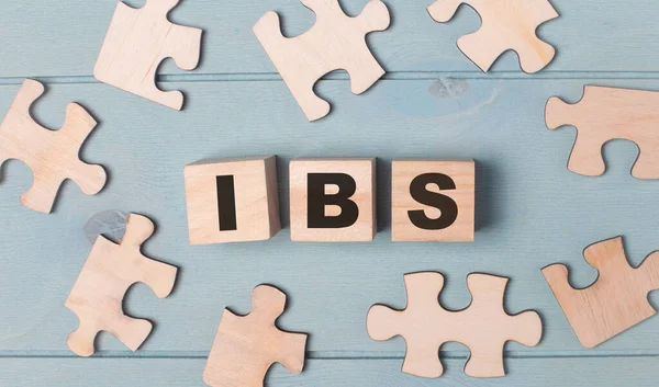 Blank puzzles and wooden cubes with IBS lie on a light blue background.