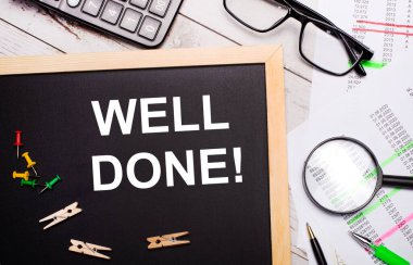 Masaüstünde hesap makinesi, raporlar, gözlükler, büyüteç, kalemler ve mandallı bir pano var. İş konsepti.