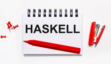 Hafif bir arka planda, kırmızı bir kalem, kırmızı bir zımba, kırmızı ataç ve üzerinde HASKELL yazan bir defter.