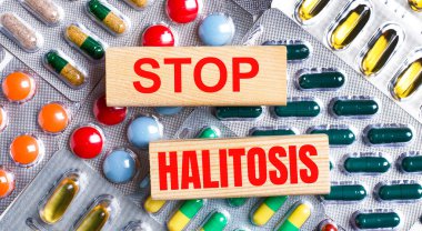 Çok renkli plakaların arka planına karşı, DUR HALITOSIS yazılı ahşap bloklar. Tıbbi konsept.