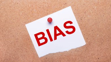 Üzerinde BIAS yazan beyaz kağıt, ahşap arka plana kırmızı bir düğmeyle iliştirilmiş..