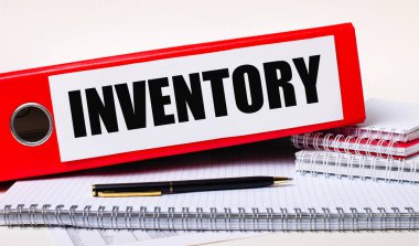 Masaüstü üzerinde INVENTORY metni ile kağıtlar için bir kalem ve kırmızı klasör bulunmaktadır. İş konsepti