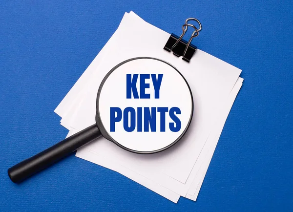 On a blue background, white sheets under a black paper clip and on them a magnifying glass with the text KEY POINTS