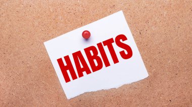 HABITS yazılı beyaz kağıt kırmızı bir düğme ile ahşap arka planda eklenmiştir.