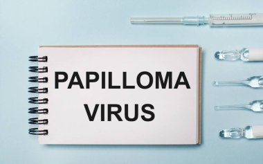 İlaçlı mavi arka plan ampulü ve içinde PAPILLOMA VIRUS yazan bir defter. Tıbbi konsept