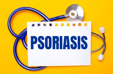 Parlak sarı bir zemin üzerinde mavi bir steteskop ve PSORIASIS yazılı bir kağıt. Tıbbi konsept