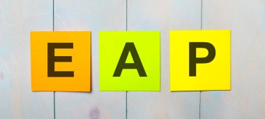 Açık mavi ahşap arka planda EAP Personel Yardım Programı yazılı üç renkli etiket