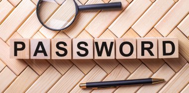 Üzerinde PASSWORD yazan tahta küpler büyüteçle kalem arasındaki tahta zemin üzerinde dururlar.