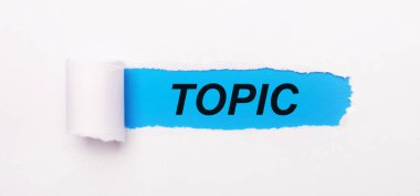 Parlak mavi arkaplanda, yırtık çizgili beyaz kağıt ve TOPIC metni