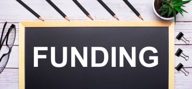 Açık ahşap bir masanın üzerinde. Üzerinde yazı, kalem, bitki, bardak ve ataç olan bir tahta. İş konsepti