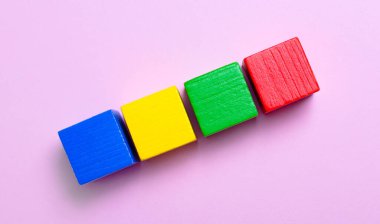 Açık pembe arka planda, çok renkli ahşap küpler ve metin eklemek için bir yer.