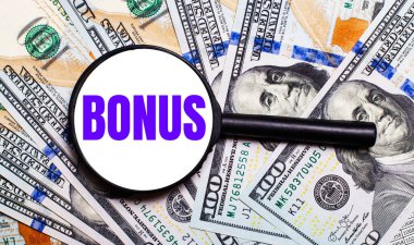 BONUS yazılı bir büyüteç altında dolar banknotları olan bir arka plan. Mali konsept