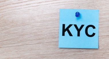 Açık ahşap bir arka planda - KYC CUSTOMER BİLİYOR yazılı açık mavi kare bir etiket
