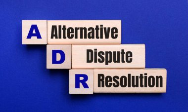 On a bright blue background, light wooden blocks and cubes with the text ADR Alternative Dispute Resolution clipart