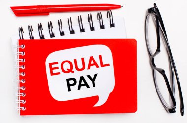 Beyaz arka planda, beyaz ve kırmızı not defterleri, siyah gözlükler, kırmızı bir kalem ve EQUAL Ödeme yazılı beyaz bir kart.