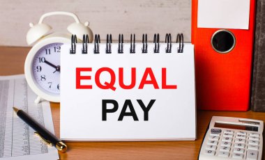 Masada raporlar, bir beyaz alarm saati, bir hesap makinesi, kağıtlar için klasörler, bir kalem ve EQUAL Ödeme yazılı beyaz bir defter var. İş konsepti