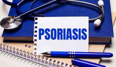 Masanın üzerinde not defterleri, bir steteskop, bir kalem ve PSORIASIS yazılı bir kağıt var. Tıbbi konsept