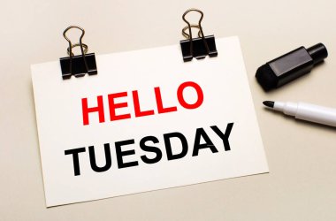 Açık bir arkaplanda, siyah bir işaretleyici ve siyah ataçlar üzerinde beyaz bir kağıt sayfası Hello Salı