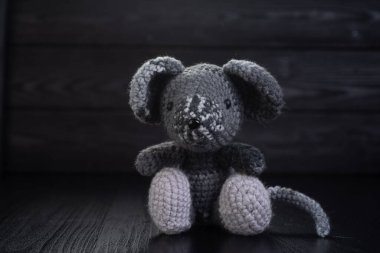 Gri örülmüş fare el yapımı siyah ahşap bir arka planda oturur