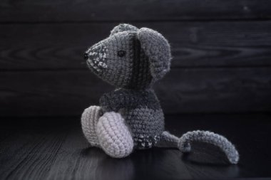 Gri örülmüş fare el yapımı siyah ahşap bir arka planda oturur