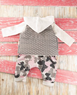 Kapüşonlu, yelekli ve tahta pembeli küçük bir kız için güzel elbiseler.