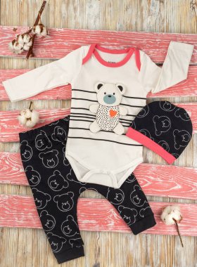 Tahta masadaki oyuncak ayılı bebekler için bebek kıyafetleri.