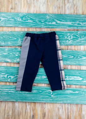 Ahşap masada yatan çocuk için çizim hücresi olan şık pantolonlar.