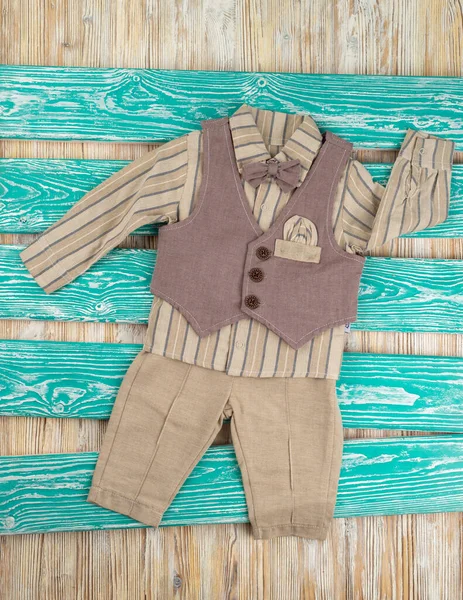 Tahta arka planda bebek resmi olan sevimli kahverengi takım elbise.